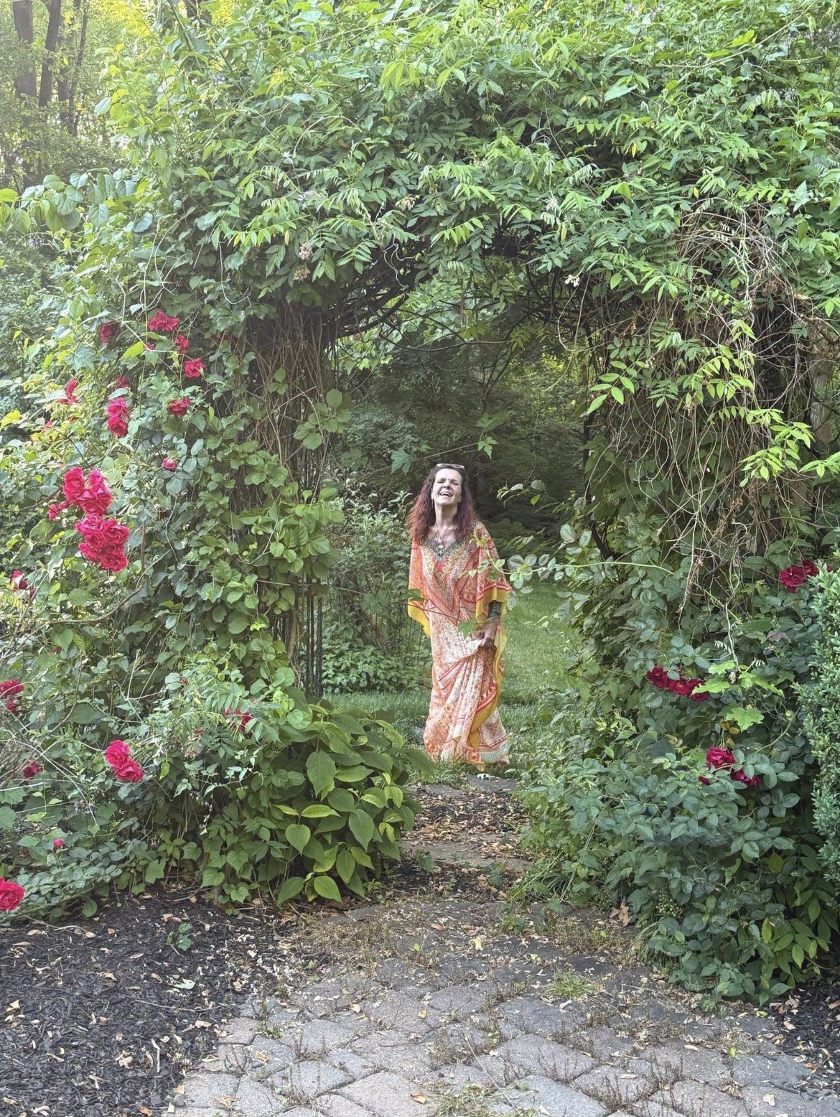 Capella smiling in a lush garden framed by roses
